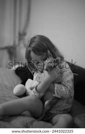 Child sits on bed and hugs cat