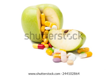 Colored pills and green apple. Diet concept isolated on white background