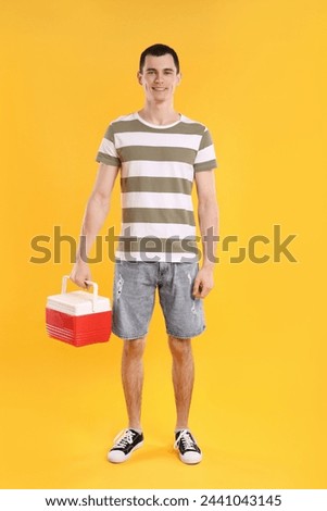 Man with red cool box on orange background