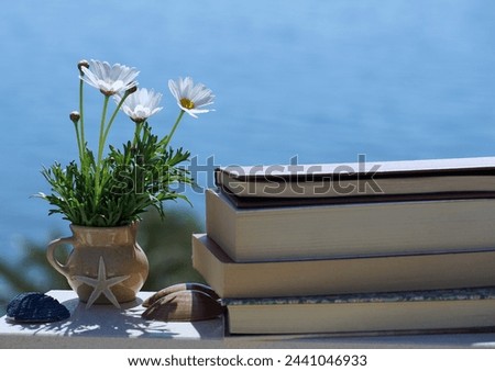 Enjoy the calm summer vacation memories with books, flowers and sea shells on the blue background