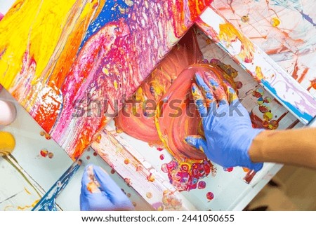 Young Asian generation z man learning acrylic pouring art on canvas workshop at art studio. Happy people artist enjoy and fun indoor hobbies creating colorful abstract modern art painting in class.