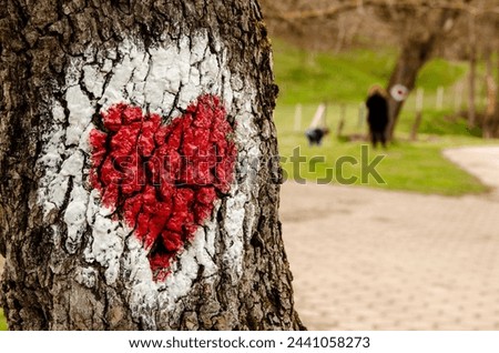 Graffiti of a red heart in a white circle drawn on the bark of a real tree