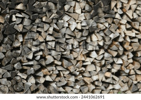 photograph of neatly stacked firewood creating a great background of neutral gray and tans with black