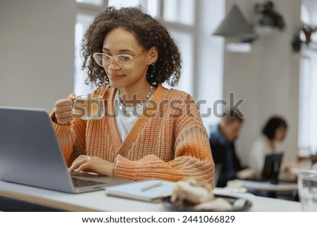 A freelancer worker uses a laptop on a table with a cup of coffee Royalty-Free Stock Photo #2441066829