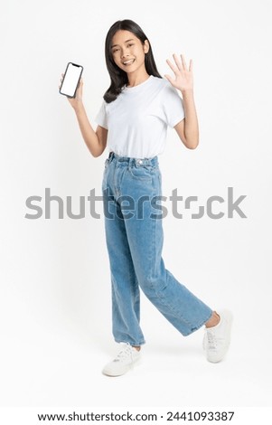 Happy casual Asian girl student holding smartphone mockup of blank screen on white background.