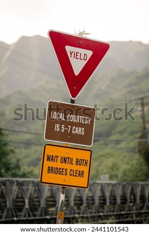 A sign at a bridge on the island of Kauai asking drivers to drive not more than 5-7 cars in a row and then letting the other side pass through. Yield sign on a Hawaiian bridge