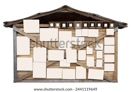 Many different paintings hung on the wall of a rustic barn. Isolated on white