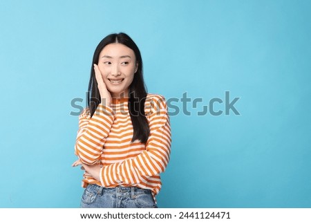 Portrait of happy woman on light blue background. Space for text