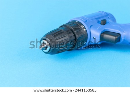 A small electric screwdriver screwdriver on a blue background. A tool for tightening screws.