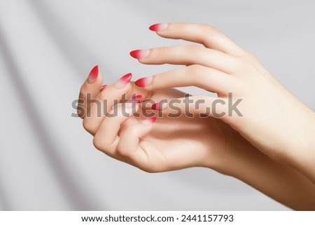 Nail design, manicure with gel polish. Women's hands with a gradient red manicure. Beautiful woman's hands with ombre gradient nail design. Manicure, pedicure beauty salon concept.