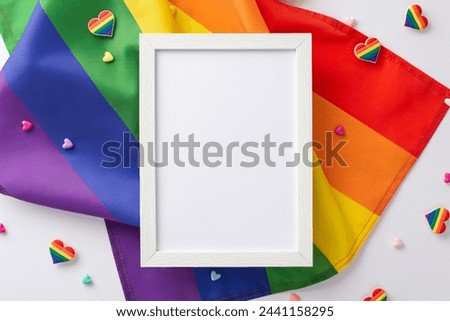 A top-down view of LGBT-themed accessories, including a photo frame, rainbow flag, pin badges, and heart ornaments, arranged on a white surface with a blank space for text or picture