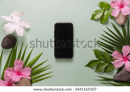 Smartphone with spring flowers on green background. 