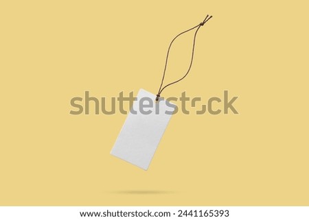 Blank price tag tied with string float on yellow background