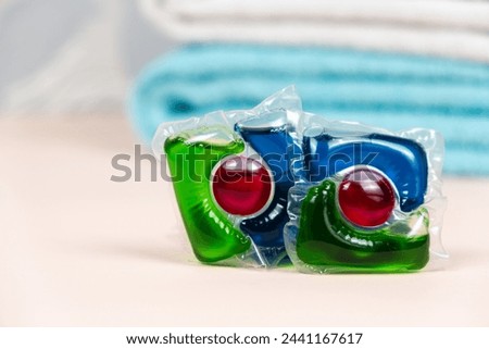 Laundry pods capsules on beige background with soft towels