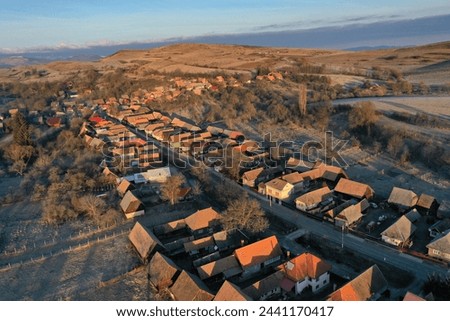 Aerial drone view of residential houses in a village during morning sunrise lights