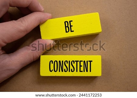 Be consistent words written on wooden blocks with brown background. Conceptual symbol. Copy space.