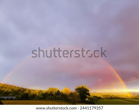 pictured landscape and a big colorful rainbow at the sky 