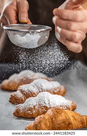 Close-Up of Chef's Hand Sprinkling Powdered Sugar on Croissants with Sieve in Kitchen in 4K Ultra HD Resolution 