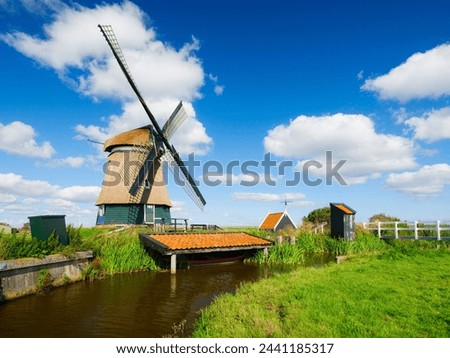An old mill in the Netherlands. Historical building. A mill near a canal. Dutch architecture and history. Photo for postcard or background.