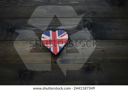 wooden heart with national flag of great britain near reduce, reuse and recycle sing on the wooden background. ecological concept