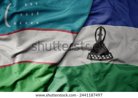 big waving national colorful flag of lesotho and national flag of uzbekistan. macro