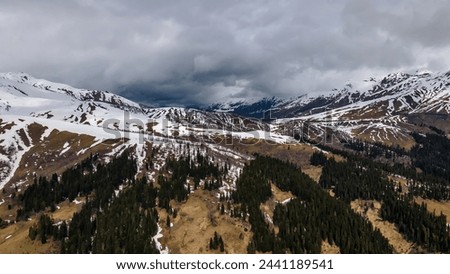 Beautiful mountain landscape. Clouds in the sky. Green grass. Snow on mountain peaks.	