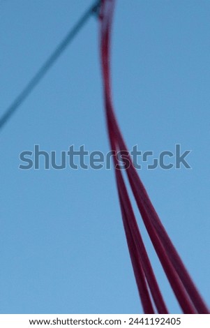 Abstract Elegance: Soft Focus on Red Cables against a Blue Sky