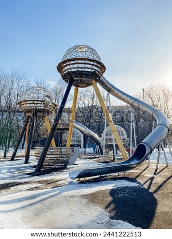 A playground with a slide shaped like a spaceship under the sky, surrounded by trees and water, offering leisure and recreation in a scenic landscape