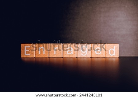 Wooden blocks form the text "Enraged" against a black background. Royalty-Free Stock Photo #2441243101