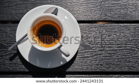 Banner with a white cup with strong black coffee on a black table in a street cafe, top view and space for advertising concept or text