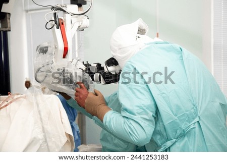 A neurosurgeon doctor looks into a microscope during an operation. Neurosurgery and microsurgery. 