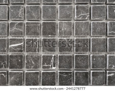 Gray ceramic tiles in mosaic pattern. Finishing material on exterior or interior bathroom wall. Abstract architecture detail. Checkered background with regular ormanent structure of squares.