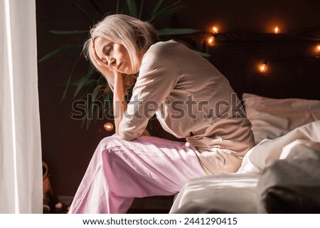 Upset middle-aged woman sit on bed in bedroom lost in thoughts thinking pondering of problem solution, depressed unhappy mature female look in distance suffer from depression, having personal problems Royalty-Free Stock Photo #2441290415