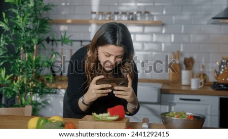 Girl taking picture or recording video with smartphone the vegetables and fruits on kitchen table. Blogger woman preparing food, taking pictures on phone for her social accounts or video stories