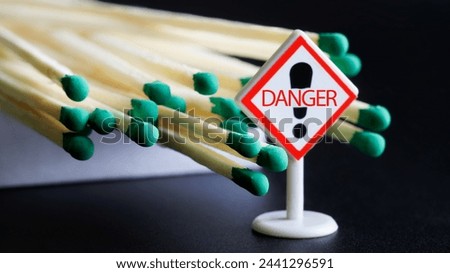 An open matchbox next to a Danger warning sign. Concept for teaching children and adults about fire safety. Black background. Macro. Selective focus. Close-up
