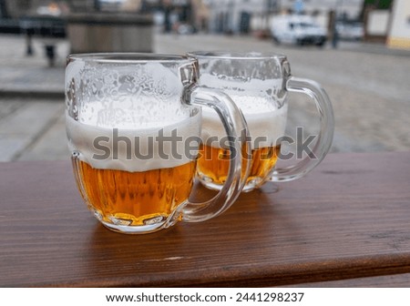 Beer mugs or beer glasses on wooden table top city at the background.