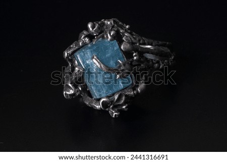A beautiful silver ring with  blue multi-faceted stones against a dark background. It emits an ethereal glow, accentuating its natural imperfections. Perfect for advertising jewelry and stylish look.