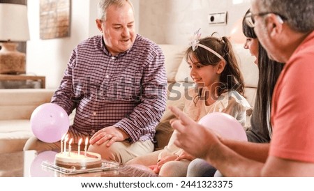 Girl about to blow the candles of a birth cake with her family at home