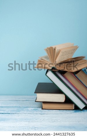 Book stacking. Open book, hardback books on wooden table and blue background. Back to school. Copy space for text