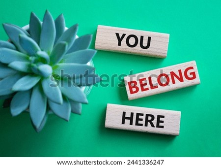 You belong here symbol. Wooden blocks with words You belong here. Beautiful green background with succulent plant. Business and You belong here concept. Copy space.