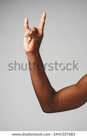 Hand Making the Rock N Roll Sign Against a Plain Gray Background