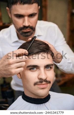 Man with mustache getting new hairstyle at barbershop Royalty-Free Stock Photo #2441341779