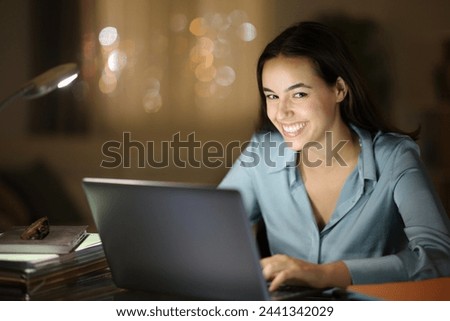 Tele worker smiling at you in the night at home Royalty-Free Stock Photo #2441342029