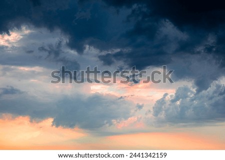 Dramatic pre-storm sky with orange-pink hues blending into dark blue clouds. Atmospheric scene before a storm. Copy space