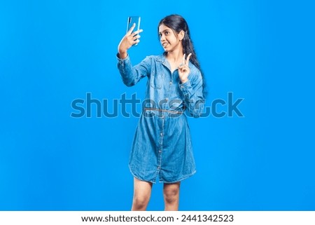 pretty indian girl posing for selfie with a smiling face and peace sign hand gesture