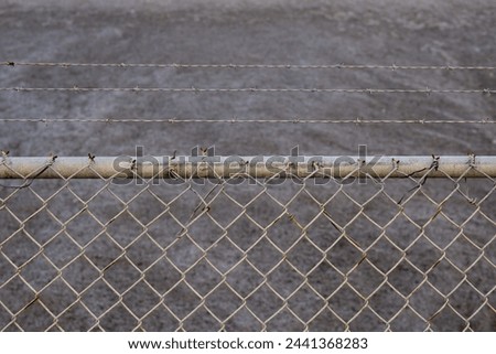 A stockpile of salt or sodium chloride road salt, halite, and rocksalt stockpiled for winter snow and ice deicing controls. The road salt is piled higher than a chainlink fence and barbed wire fence. Royalty-Free Stock Photo #2441368283