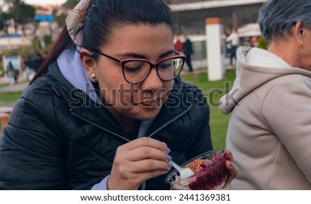 33-year-old latina woman eating blackberry dessert with milk cream and arequipe outdoor