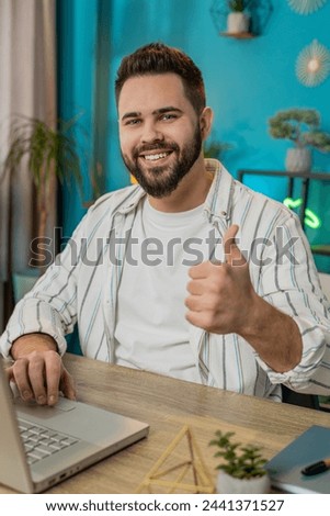 Like. Smiling young Caucasian business man looking approvingly at camera showing double thumbs up sign positive something good great news positive feedback. Happy guy at home office desk. Vertical