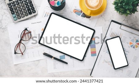 Professional financial workspace with reports, graphs, calculator, and digital devices on a marble surface.