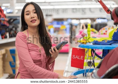 Mother woman carefully examines a modern, decision making stroller in spacious baby store, mindful parent, seeking quality and safety in children products family planning, baby care products, shopping Royalty-Free Stock Photo #2441385555